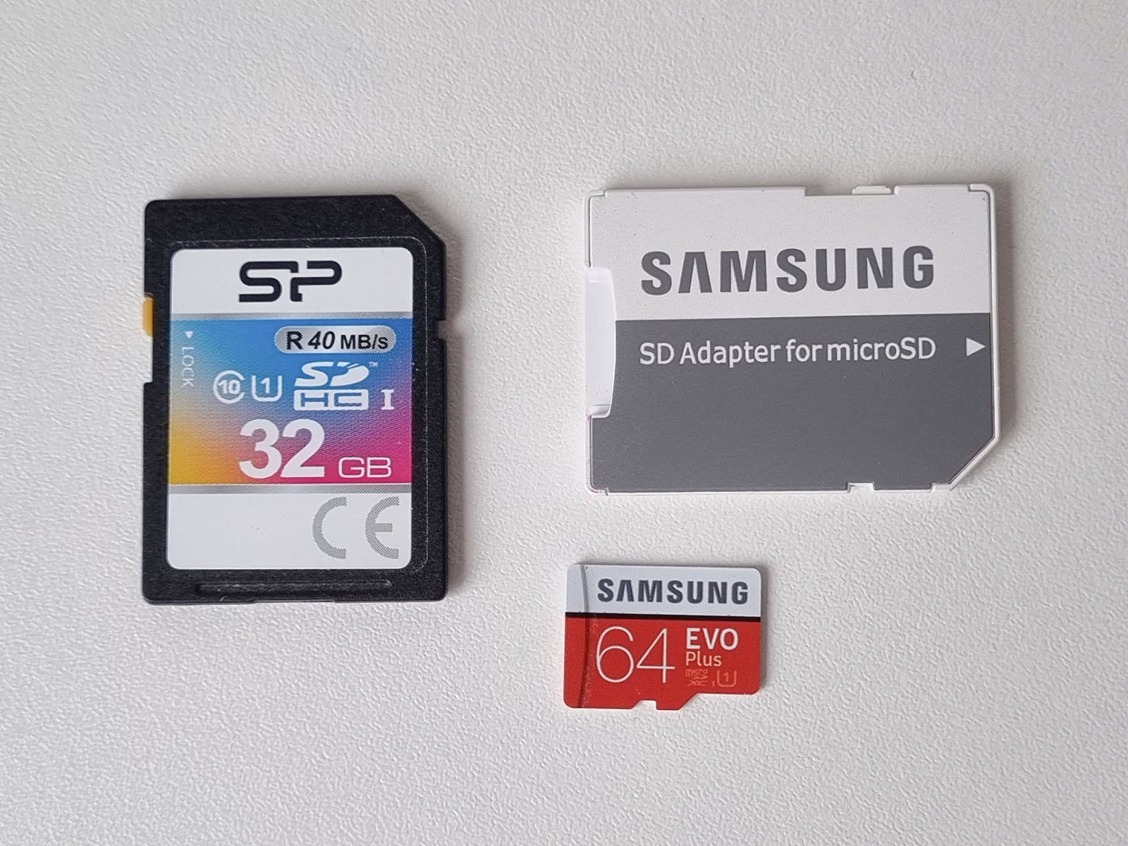 An SD card, a microSD-to-SD adapter, and a microSD card side by side, showing the range of removable card formats in common use.